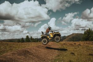 Guardian 500 ATV, springt über eine Erhebung auf einem unbefestigten Weg in hügeliger Landschaft