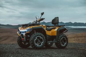 Gelbes ATV Modell Guardian 500 mit robusten Reifen und Rücksitz auf unbefestigtem Gelände