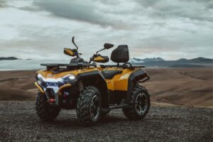 Gelbes ATV Modell Guardian 500 mit robusten Reifen, Sitz für zwei Personen und Berglandschaft