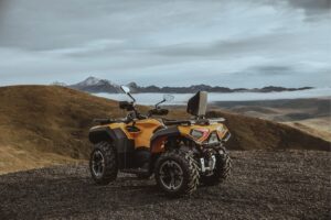 Gelbes Allrad-Quad Guardian 500 auf Schotter mit Berglandschaft im Hintergrund